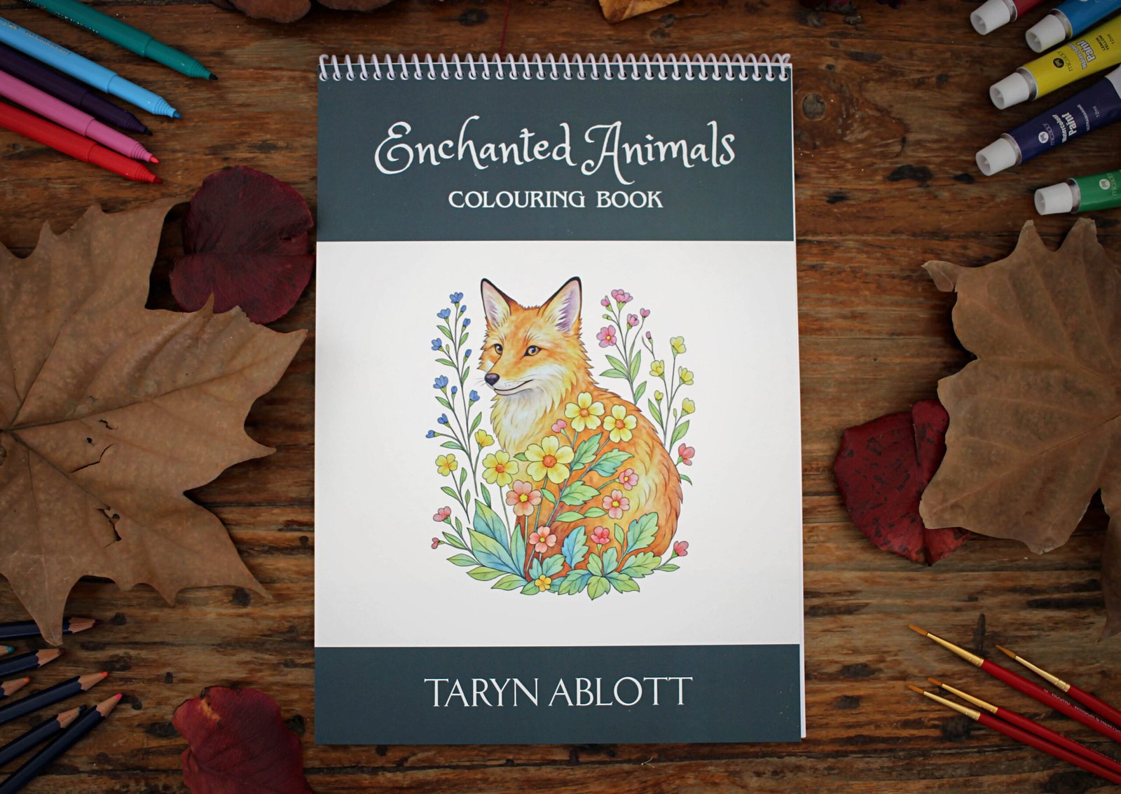 Enchanted animals colouring book on a wooden table with colouring materials.